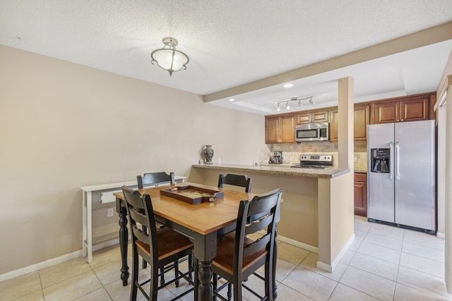 tiled dining room with a textured ceiling and track lighting