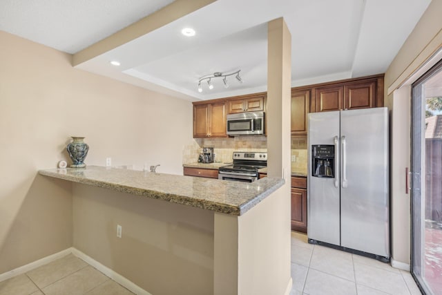 kitchen with light stone counters, appliances with stainless steel finishes, kitchen peninsula, and tasteful backsplash