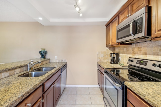 kitchen with light tile patterned floors, sink, tasteful backsplash, appliances with stainless steel finishes, and light stone countertops