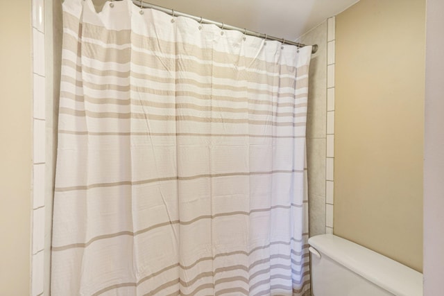 bathroom with curtained shower and toilet