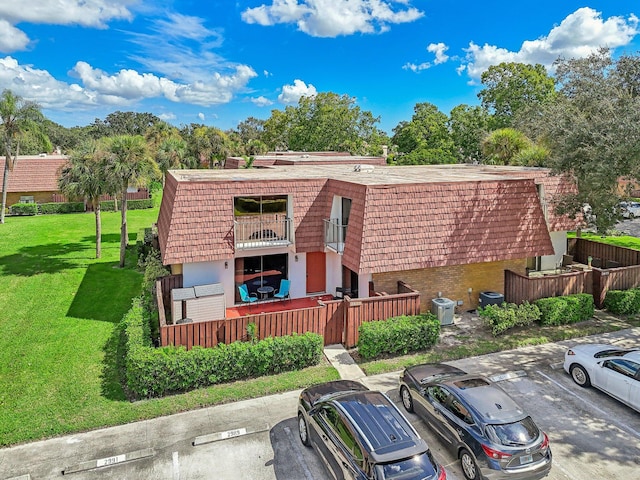 view of front of home with a front yard, a balcony, and central AC