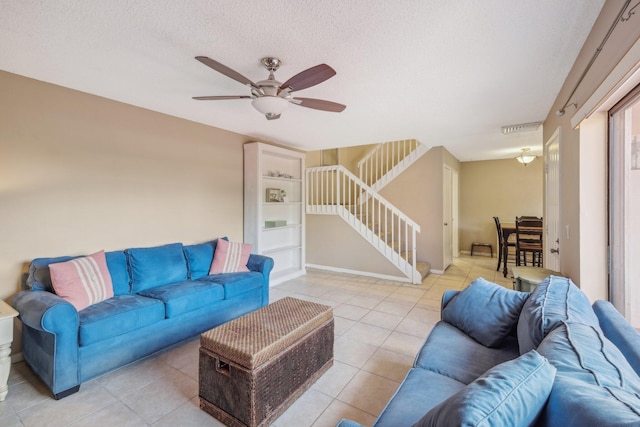 living room featuring ceiling fan, light tile patterned floors, and a textured ceiling