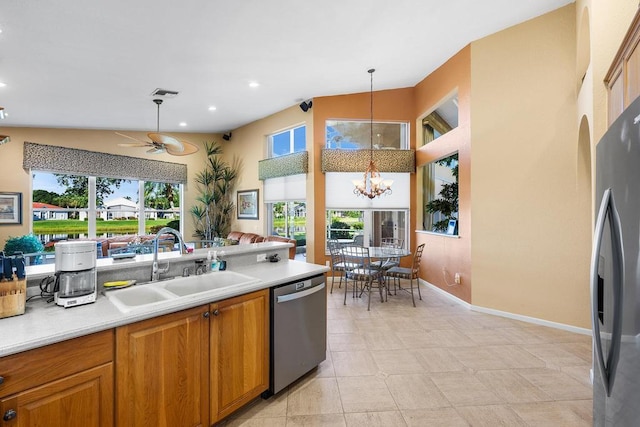 kitchen with stainless steel appliances, sink, ceiling fan with notable chandelier, pendant lighting, and vaulted ceiling