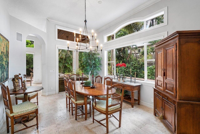 dining room with a notable chandelier, ornamental molding, and a high ceiling