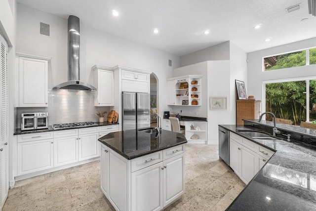 kitchen featuring dark stone counters, sink, white cabinetry, wall chimney exhaust hood, and stainless steel appliances