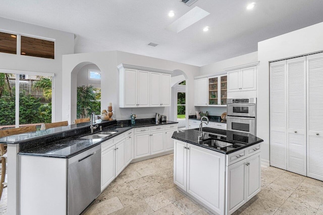 kitchen featuring stainless steel appliances, white cabinetry, kitchen peninsula, and sink