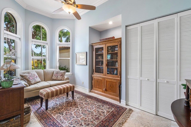 living area with ceiling fan and crown molding