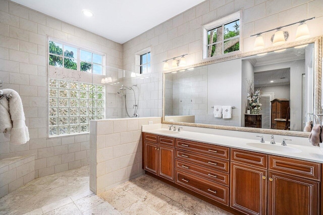 bathroom with vanity, a shower, and a healthy amount of sunlight