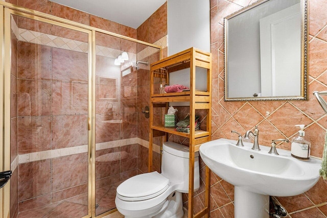 bathroom with tile walls, tasteful backsplash, a shower with shower door, and toilet