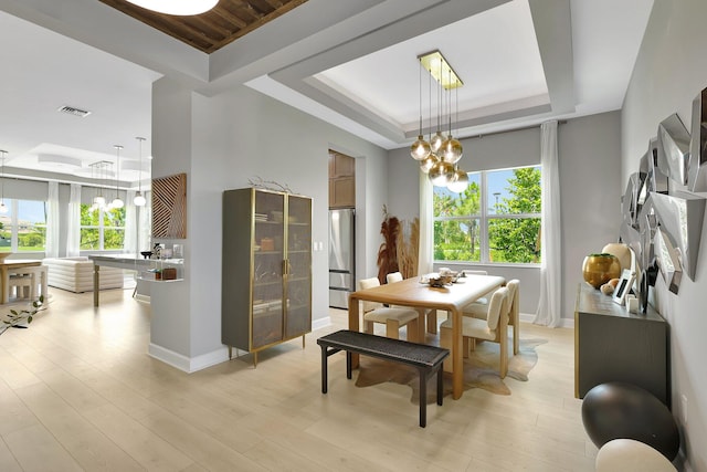 dining area with light hardwood / wood-style flooring, a chandelier, and a raised ceiling