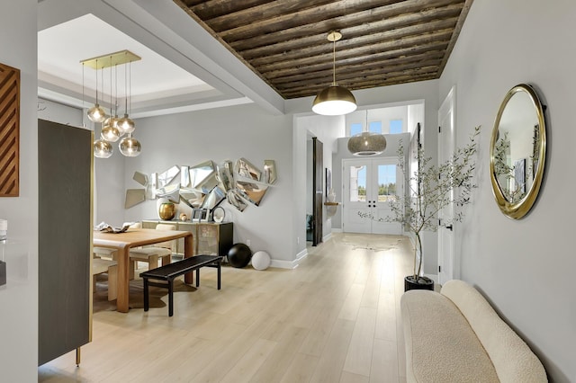 entryway with light hardwood / wood-style floors, a raised ceiling, and french doors