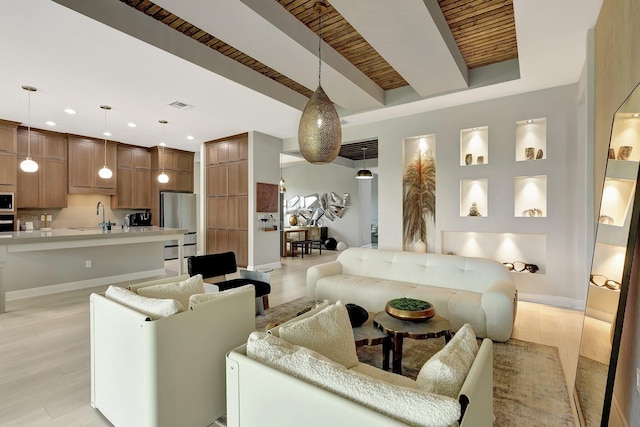 living room featuring beamed ceiling, light hardwood / wood-style flooring, and sink