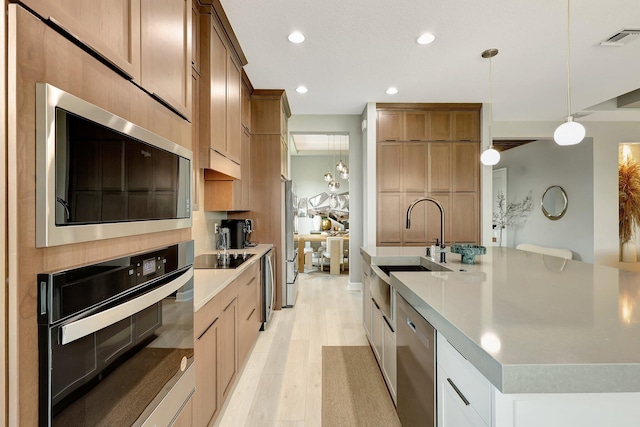 kitchen with white cabinetry, an island with sink, stainless steel appliances, light wood-type flooring, and decorative light fixtures