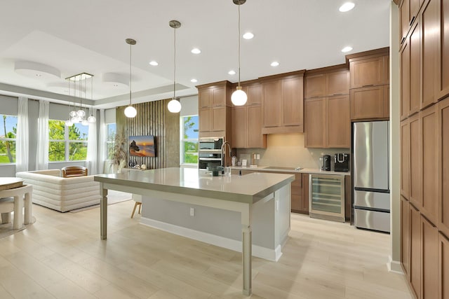 kitchen featuring pendant lighting, wine cooler, light hardwood / wood-style flooring, a center island with sink, and stainless steel appliances