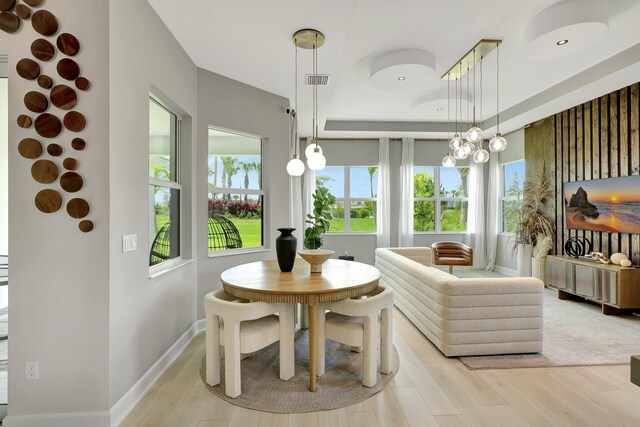 dining space with light wood-type flooring, a chandelier, and a tray ceiling