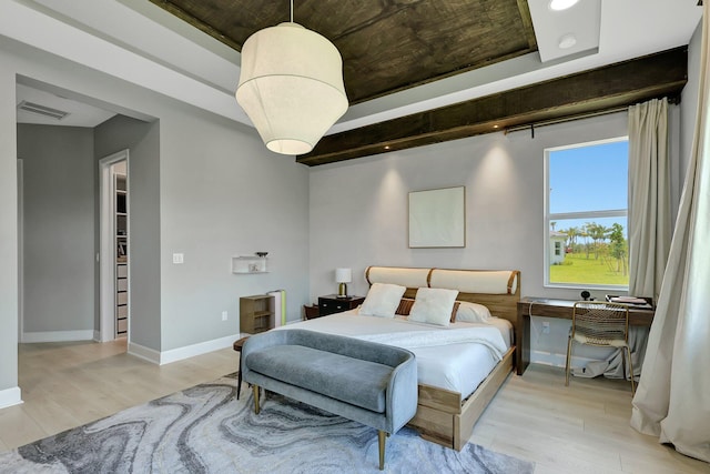 bedroom with light hardwood / wood-style flooring and a walk in closet