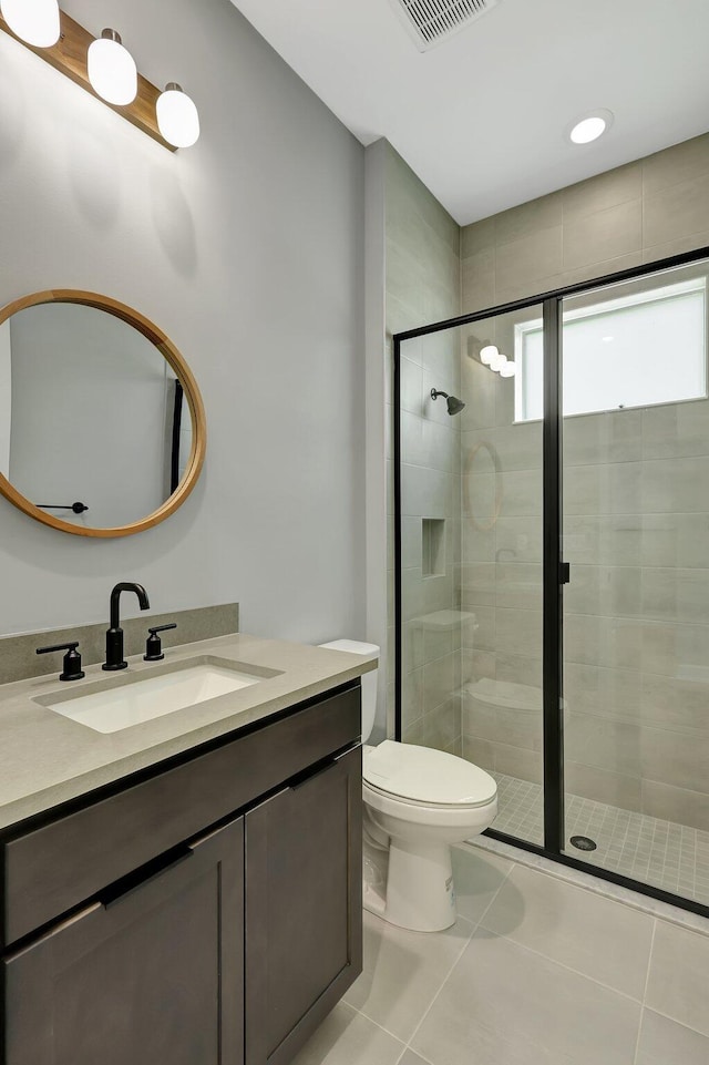 bathroom with tile patterned flooring, vanity, toilet, and a shower with shower door