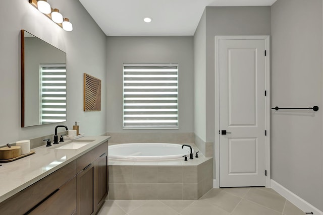 bathroom featuring tiled tub, vanity, and tile patterned flooring