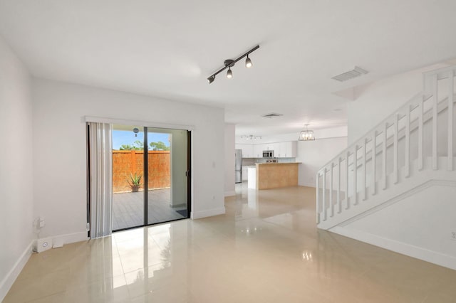 unfurnished room featuring light tile patterned floors, a chandelier, and rail lighting