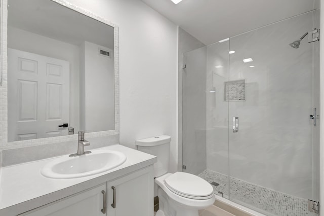 bathroom featuring vanity, a shower with shower door, and toilet