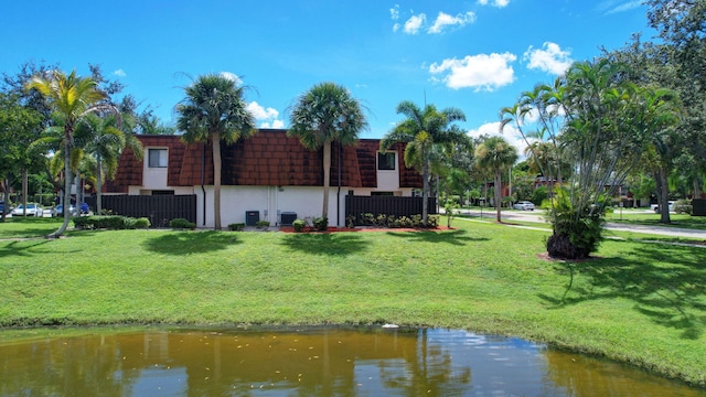 rear view of property featuring a lawn and a water view