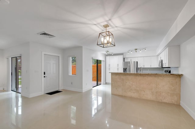 kitchen featuring appliances with stainless steel finishes, white cabinets, kitchen peninsula, light tile patterned floors, and a chandelier