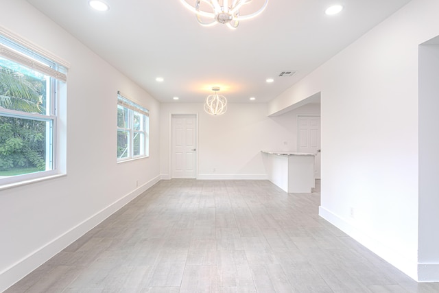 spare room with light wood-type flooring and an inviting chandelier