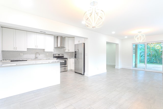 kitchen with a chandelier, white cabinetry, wall chimney exhaust hood, appliances with stainless steel finishes, and decorative light fixtures