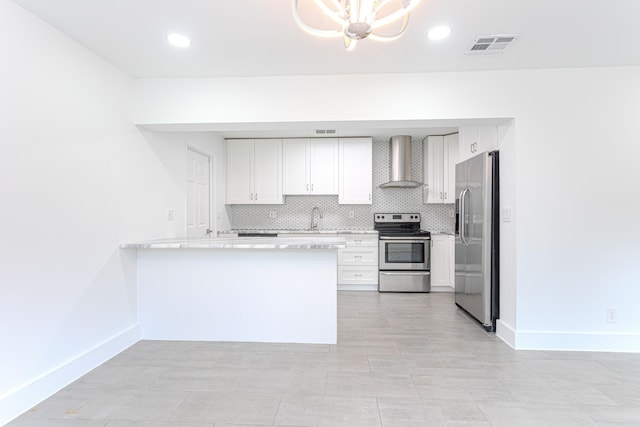 kitchen with a chandelier, white cabinetry, kitchen peninsula, wall chimney exhaust hood, and stainless steel appliances