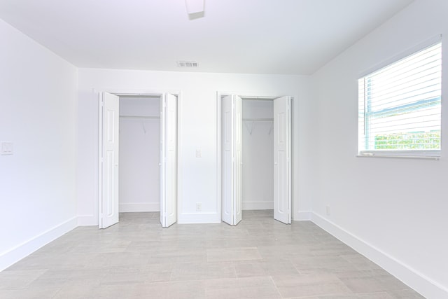 unfurnished bedroom with two closets