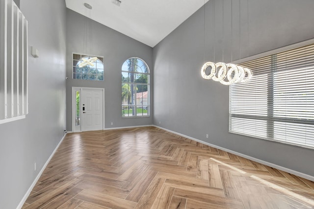 entrance foyer with light parquet floors, a notable chandelier, and high vaulted ceiling