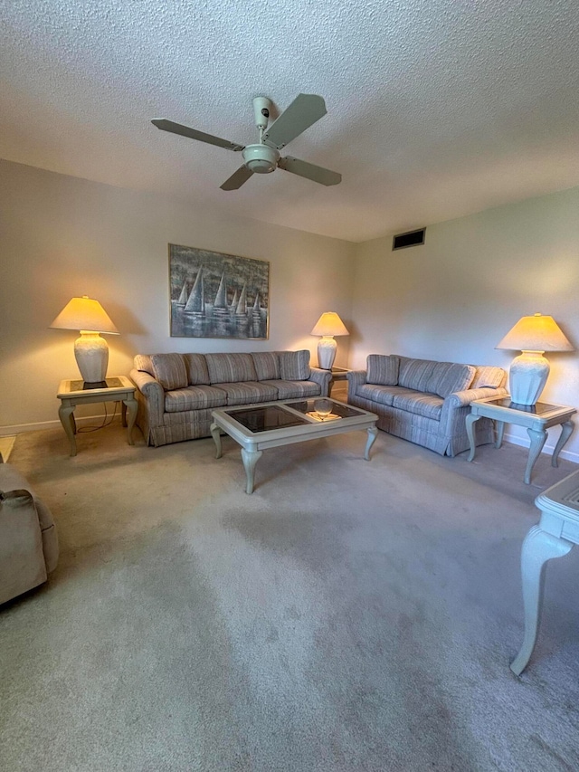 carpeted living room featuring ceiling fan and a textured ceiling