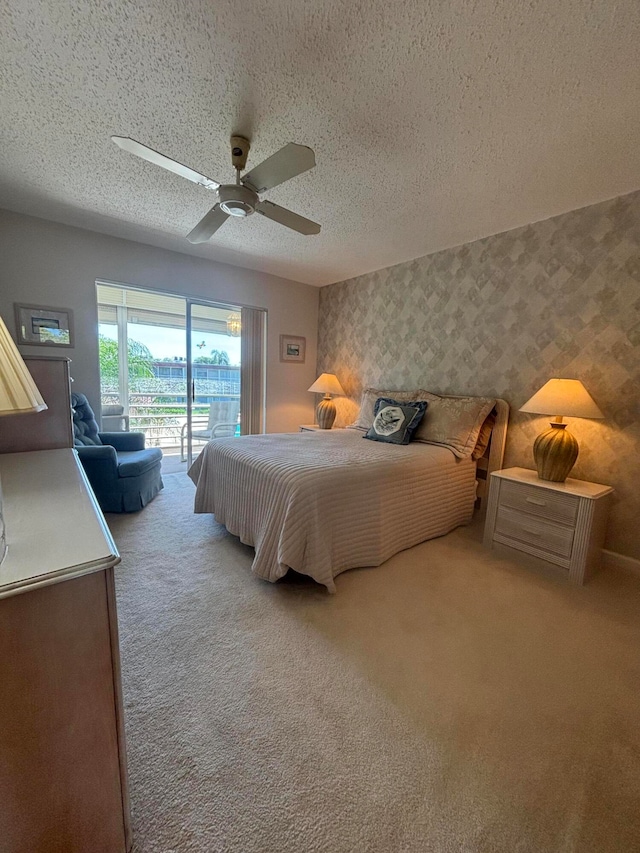 bedroom featuring access to outside, light colored carpet, a textured ceiling, and ceiling fan