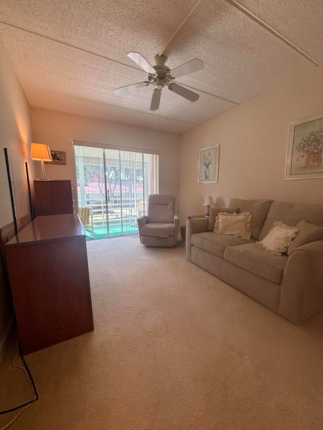 living room featuring carpet floors, ceiling fan, and a textured ceiling