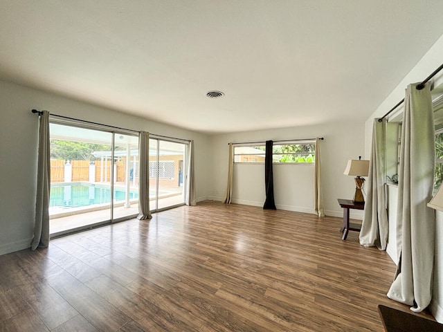 spare room with wood-type flooring and a healthy amount of sunlight