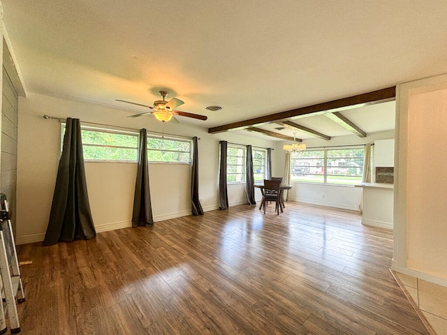 empty room with ceiling fan with notable chandelier, beam ceiling, and hardwood / wood-style flooring