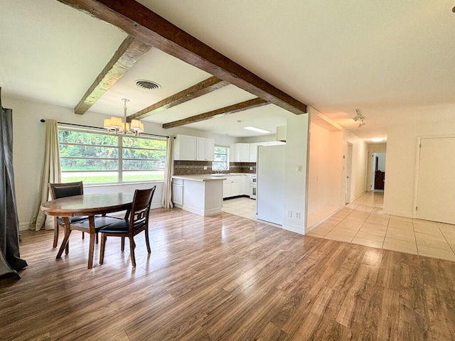 dining room with beamed ceiling, a notable chandelier, sink, and light hardwood / wood-style floors