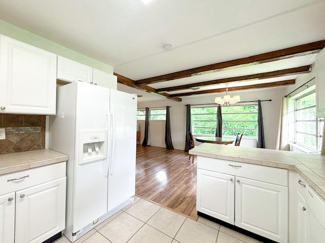 kitchen featuring an inviting chandelier, light wood-type flooring, white cabinetry, and white refrigerator with ice dispenser