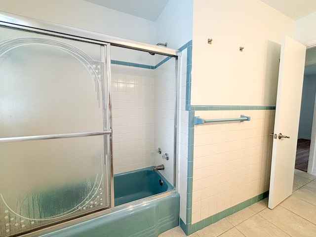 bathroom with tile walls, tile patterned flooring, and combined bath / shower with glass door