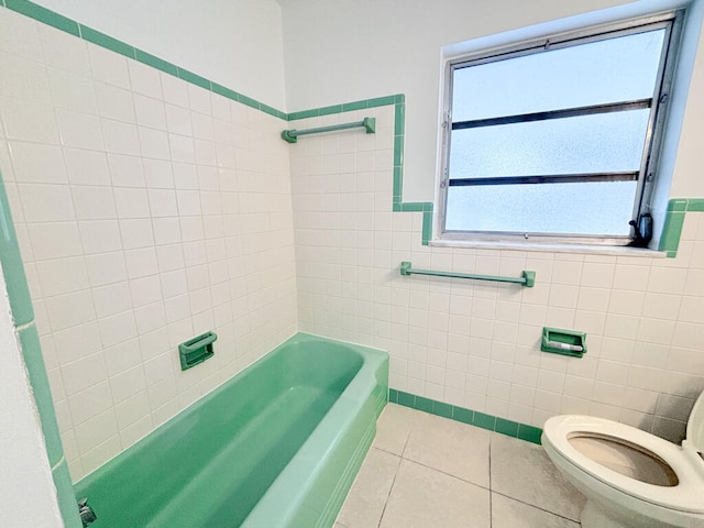 bathroom featuring tile walls, tiled shower / bath combo, tile patterned floors, and toilet