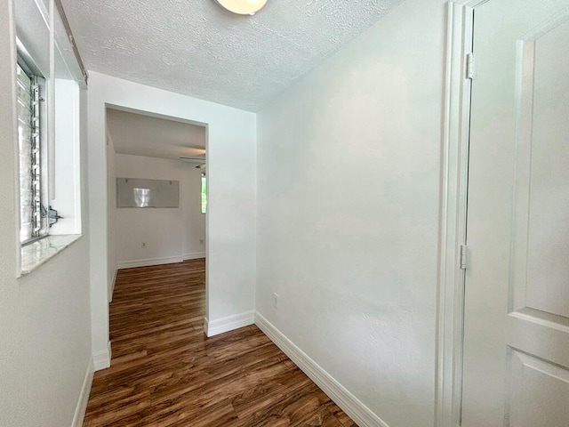 hallway featuring a textured ceiling and dark hardwood / wood-style floors