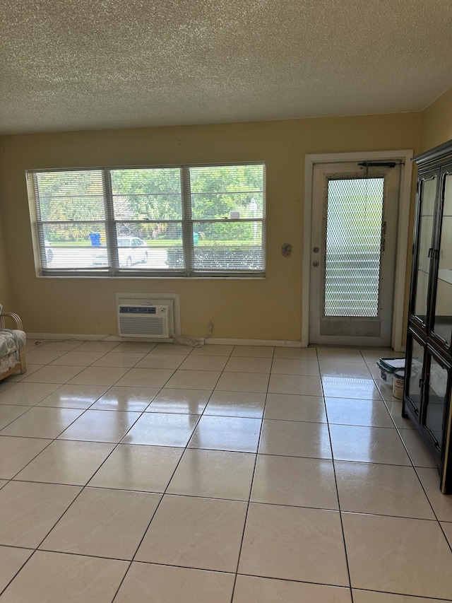 interior space featuring light tile patterned floors, a wall mounted air conditioner, and a textured ceiling