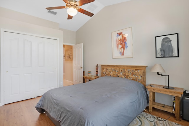 bedroom featuring light hardwood / wood-style floors, lofted ceiling, ceiling fan, and a closet