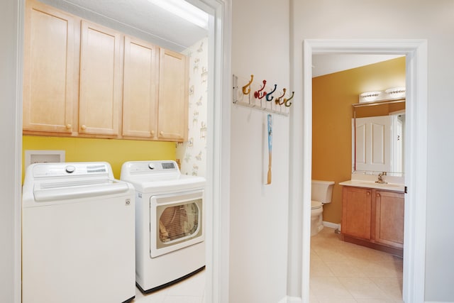 clothes washing area with cabinets, sink, light tile patterned floors, and washing machine and dryer