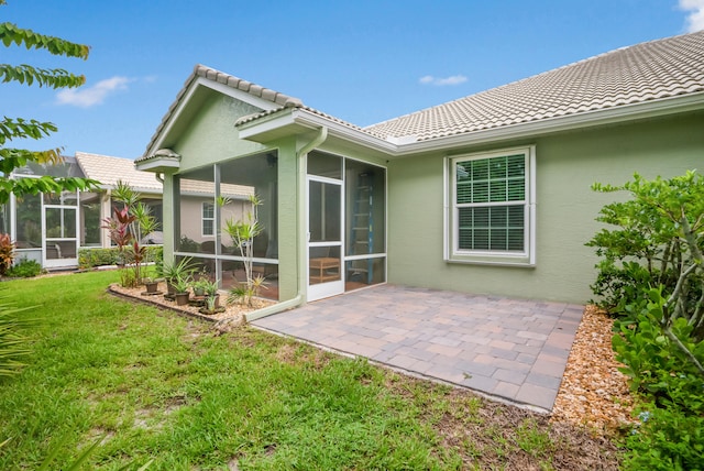 rear view of house with a sunroom, a patio area, and a yard