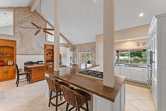 kitchen with white cabinetry, high vaulted ceiling, built in appliances, decorative backsplash, and light tile patterned floors