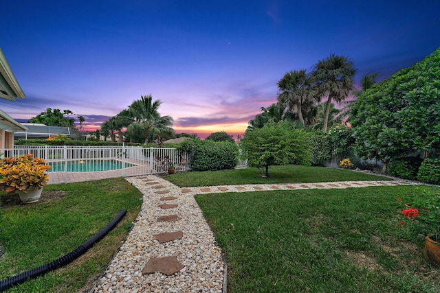 yard at dusk featuring a fenced in pool