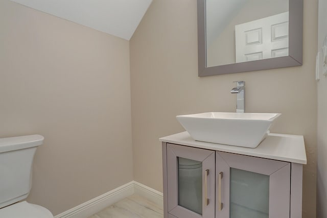 bathroom with vanity, toilet, and vaulted ceiling