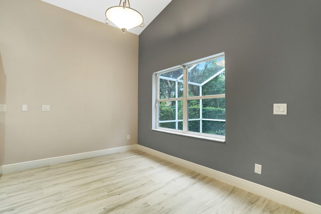 spare room with vaulted ceiling and light hardwood / wood-style floors