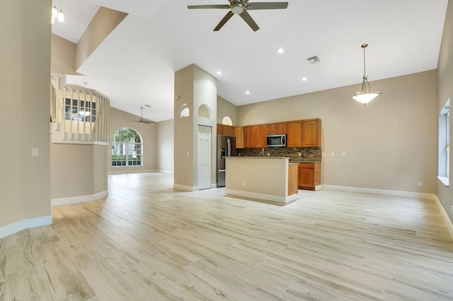 kitchen featuring ceiling fan, pendant lighting, appliances with stainless steel finishes, a center island, and light wood-type flooring